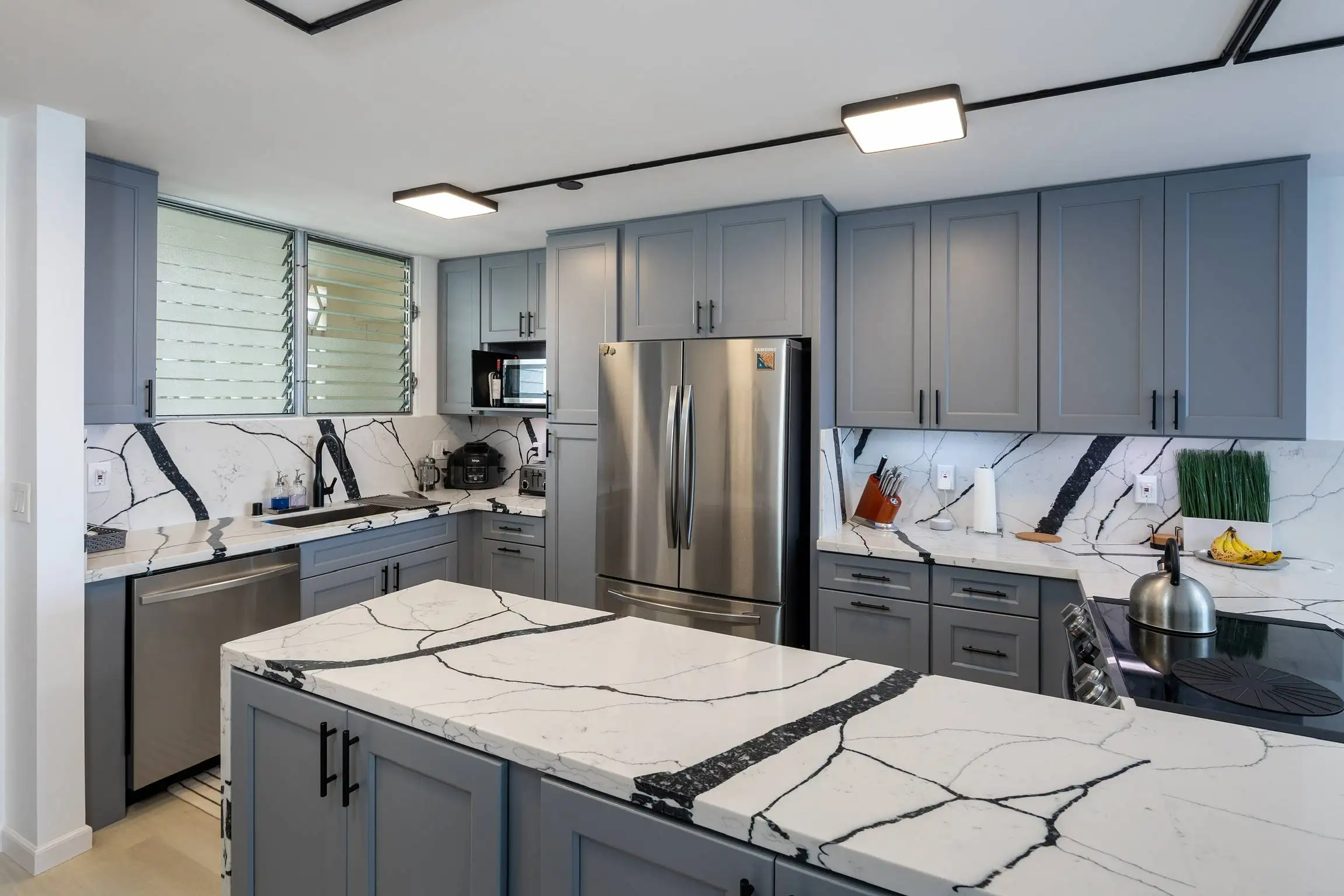 Finished Honolulu kitchen with grey shaker cabinets and veined quartz counters